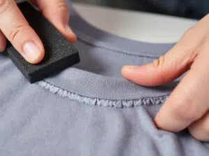 using a pumice stone to rub the edges and seams of a T shirt